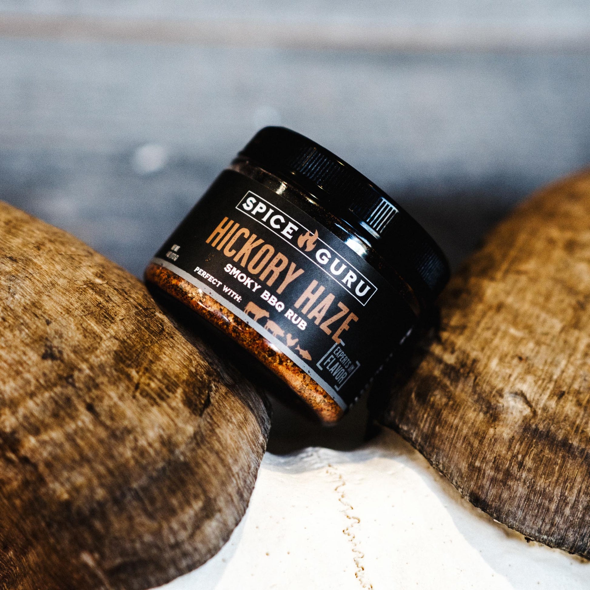 A container of Spice Guru Hickory Haze: Smoky BBQ Rub, at a jaunty angle.